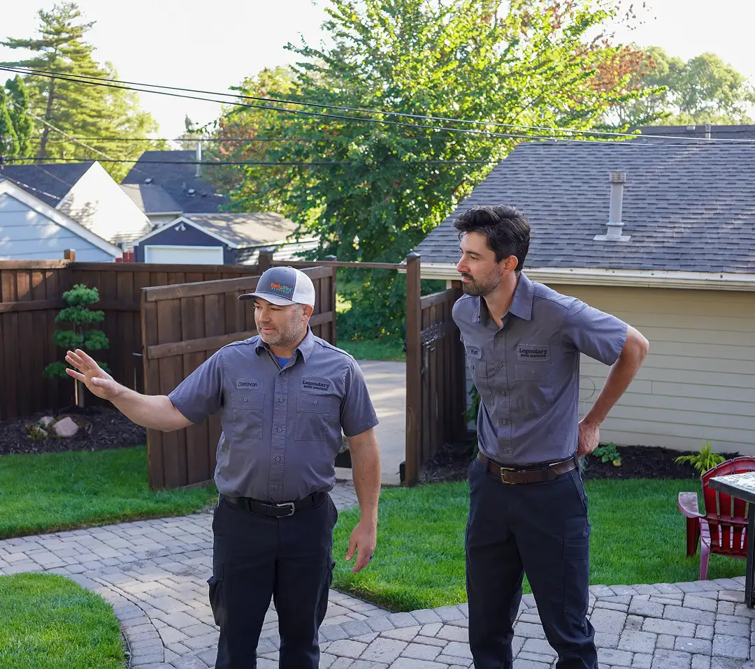 Two Legendary Home Services technicians standing outdoors near residential home
